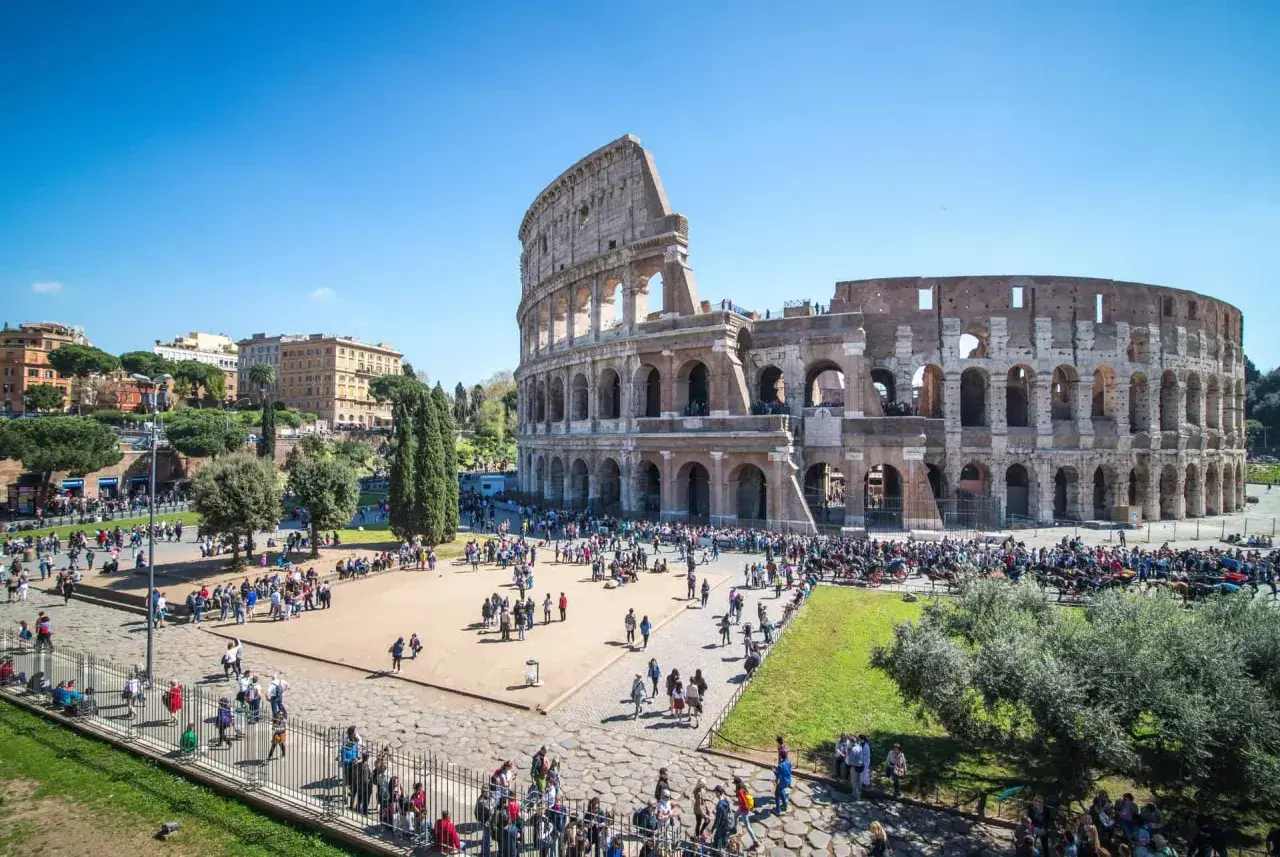 Le Colisée d'Italie, monument emblématique, accueille une foule de visiteurs sous un ciel bleu éclatant.
