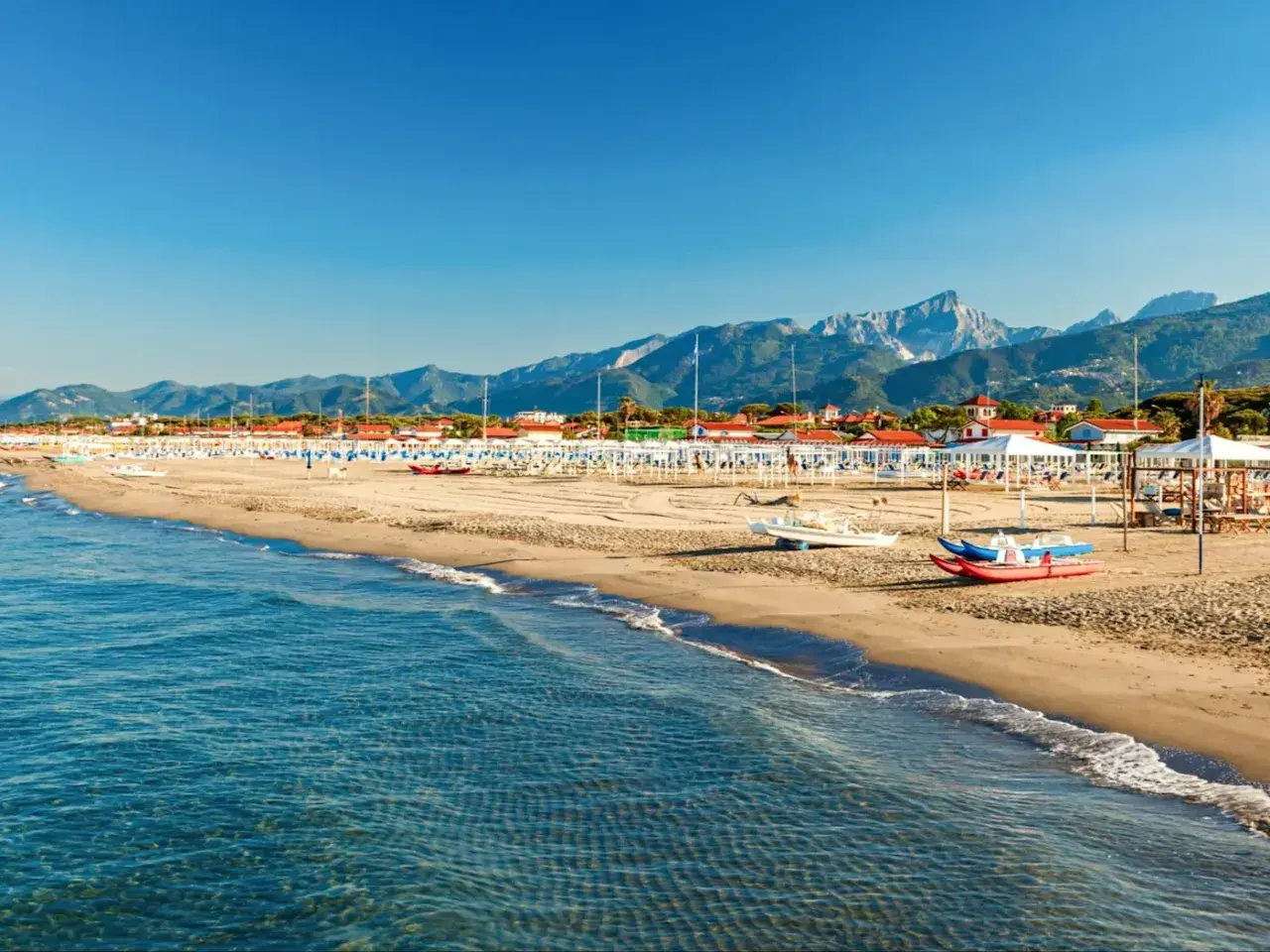 Plage de sable fin, mer bleue et montagnes en arrière-plan. Idéal pour savoir où aller en Toscane bord de mer.