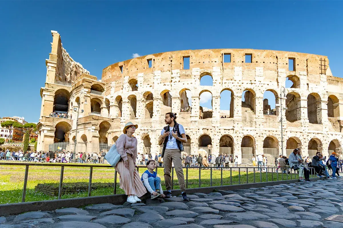 Famille admirant l'imposante arène de Rome, le Colisée, sous un ciel bleu éclatant.