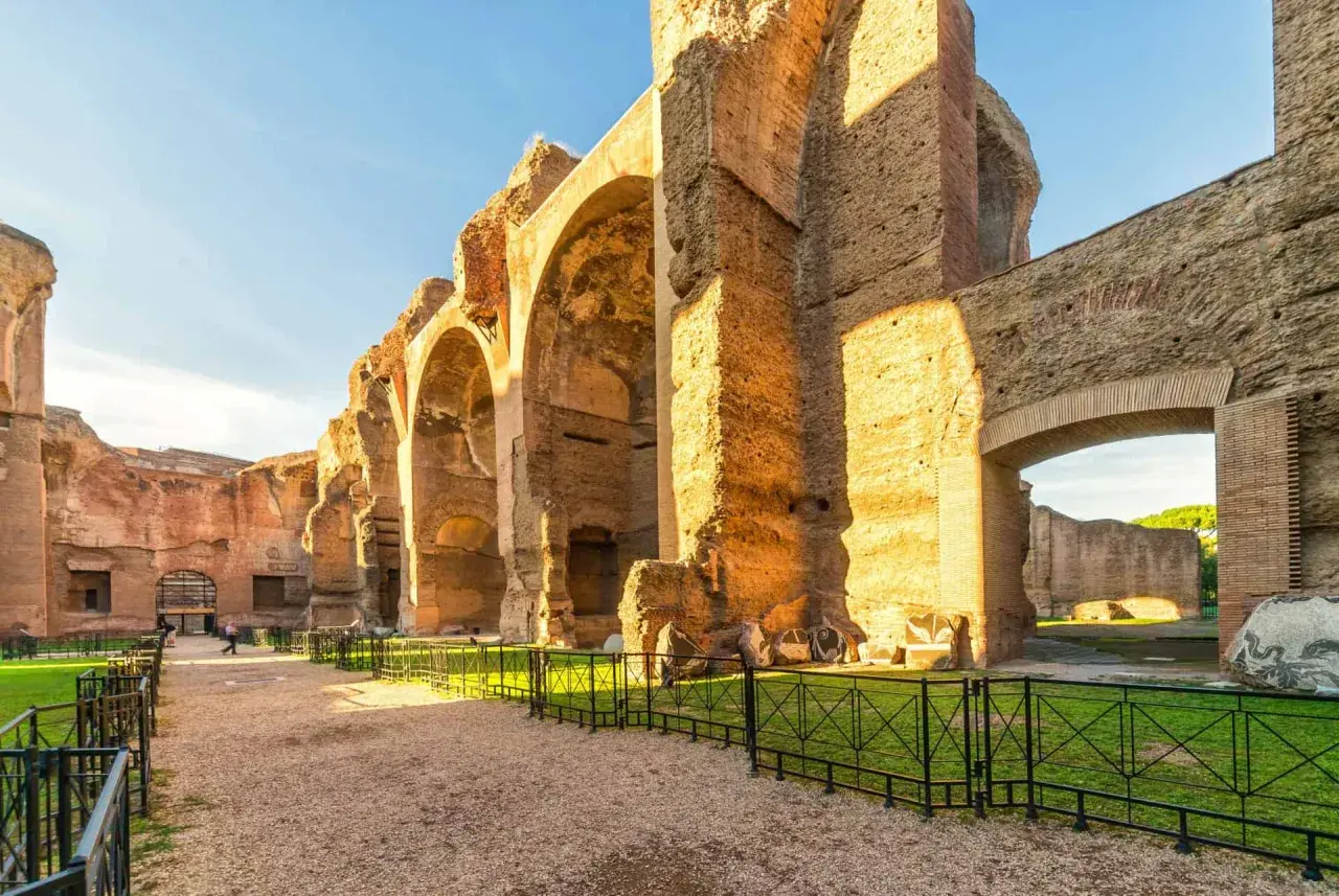 Vestiges impressionnants du **bain de Caracalla** à Rome, avec ses arches massives en briques et pierre, baignées par le soleil.