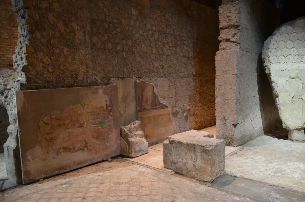Vestiges d'une fresque murale dans la maison d'Auguste à Rome, avec des blocs de pierre et des murs en ruine.