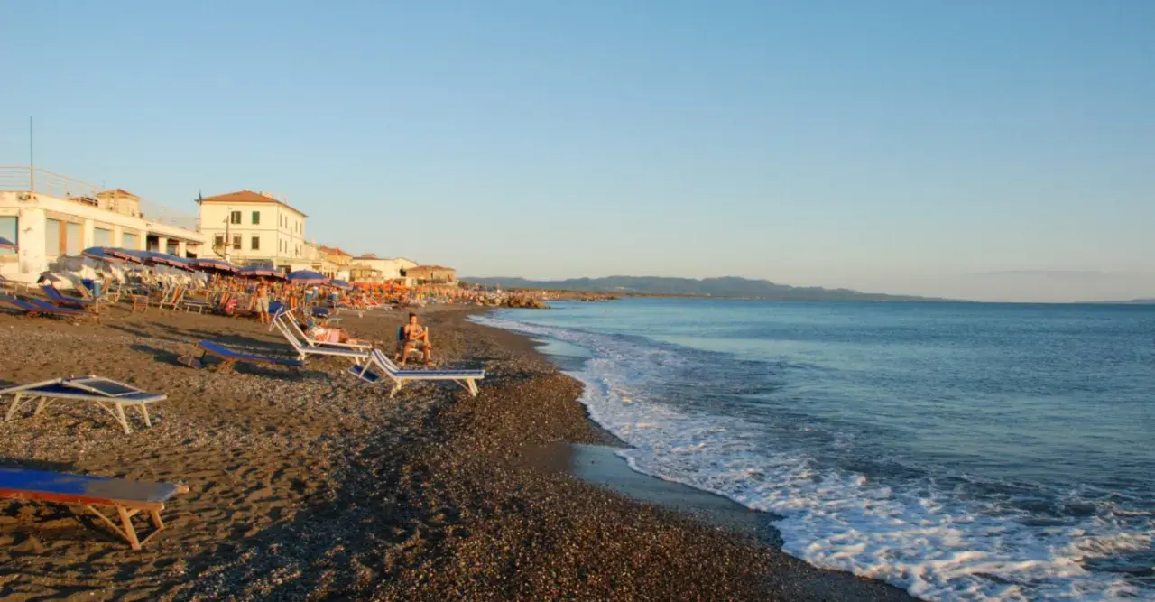 Plage de Cecina, Italie. Chaises longues et parasols sur le sable, mer calme sous un ciel bleu.