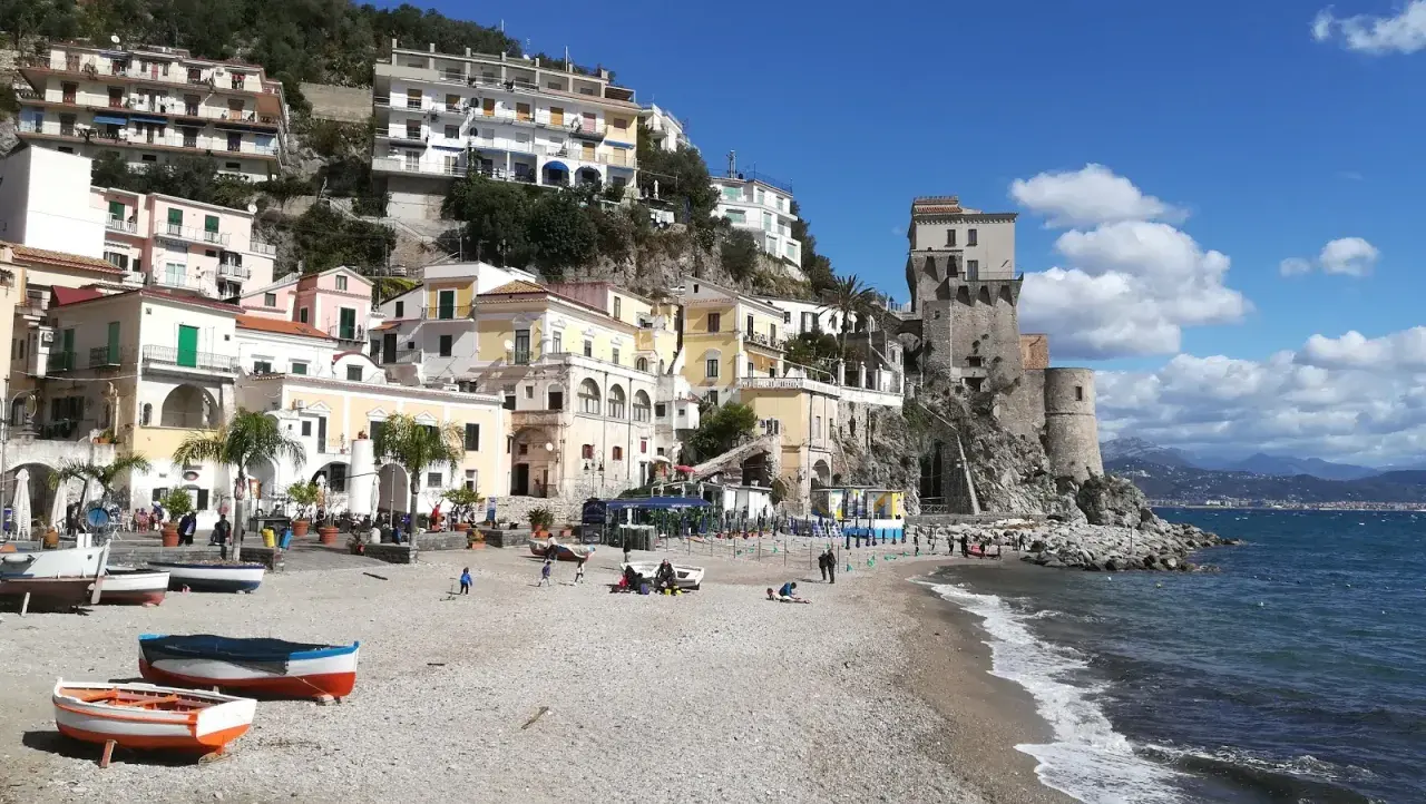 Vue pittoresque de Cetara, Italie, avec ses maisons colorées accrochées à flanc de colline et sa tour médiévale surplombant la mer.