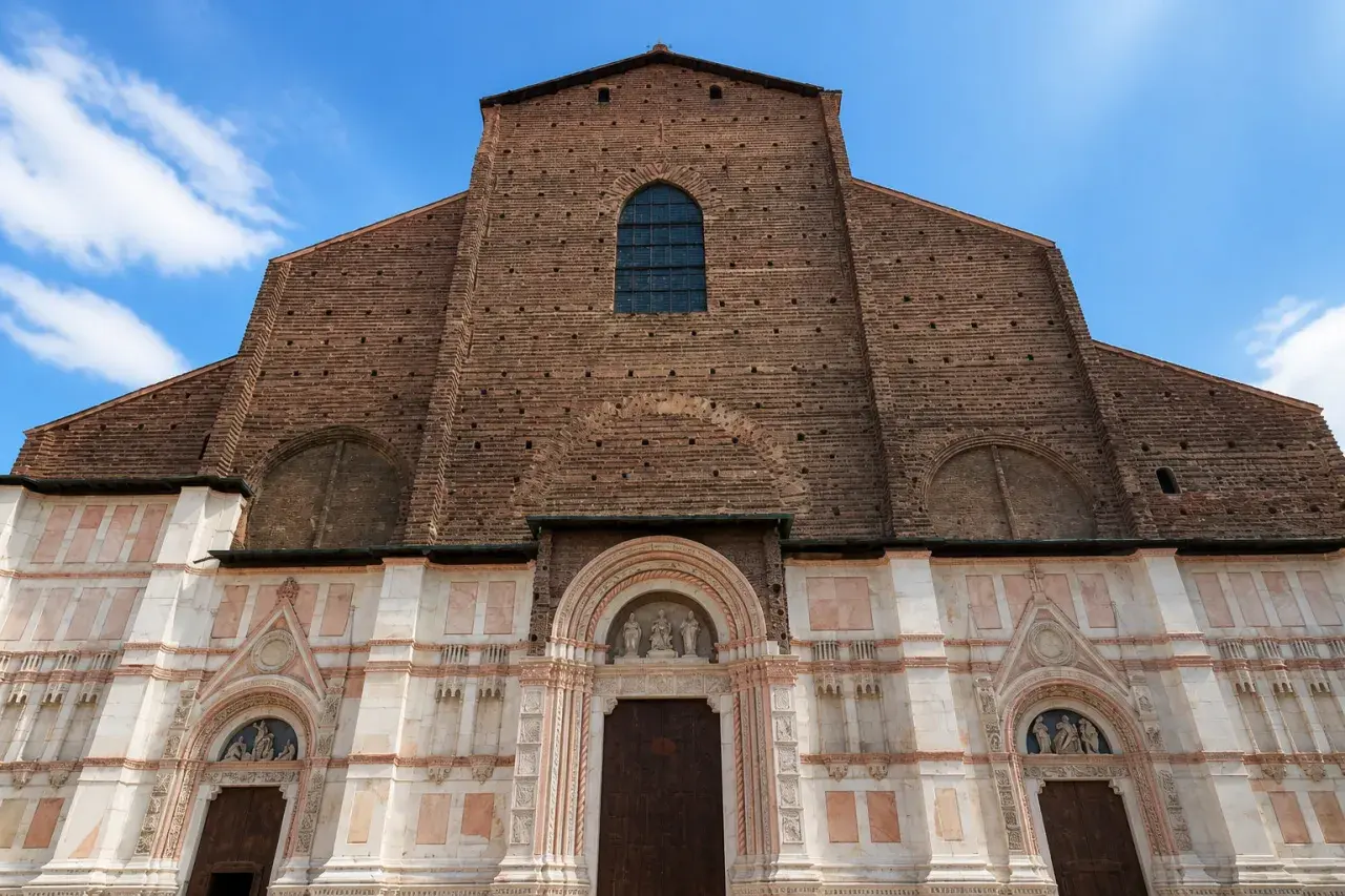 Façade imposante de la basilique San Petronio, mélange de briques rouges et de marbre blanc, sous un ciel bleu.
