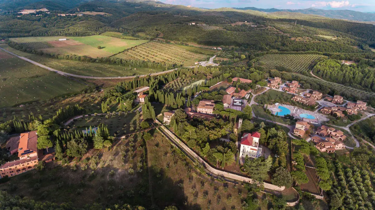 Vue aérienne du Pian dei Mucini, un domaine toscan avec des villas, des cyprès et une piscine.