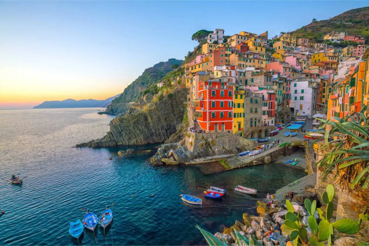 Village vacances La Spezia : maisons colorées accrochées à la falaise, bateaux dans le port, mer bleue.