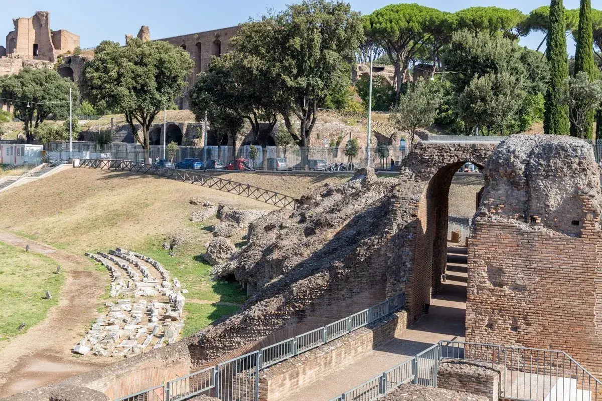 Ruines antiques du Circo Massimo à Rome, avec des gradins en pierre et une arche de briques menant à des escaliers.