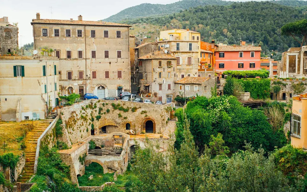 Vue d'ensemble de la Villa Gregoriana, avec ses bâtiments anciens, ses ruines et sa végétation luxuriante.