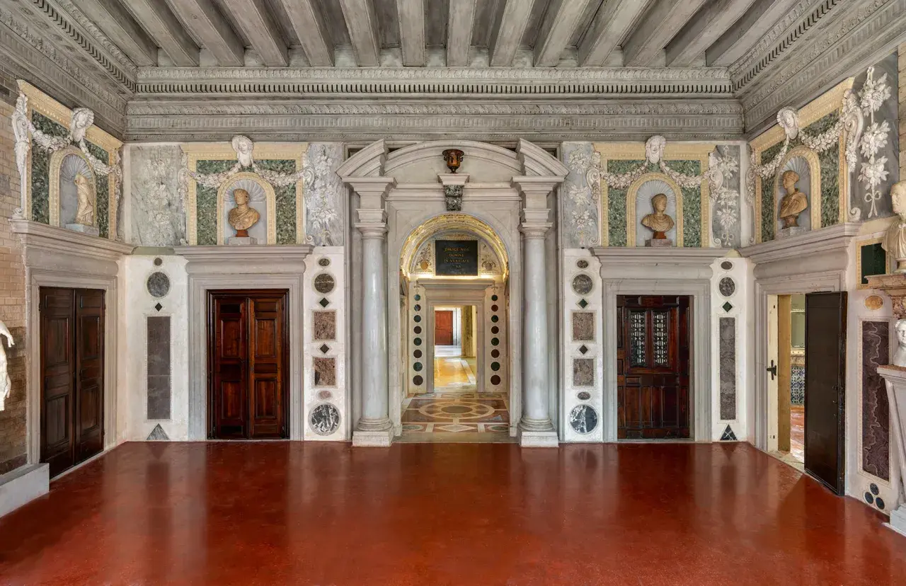 Intérieur du Palazzo Grimani, avec ses portes en bois sombres, ses bustes en marbre et ses décorations murales élaborées.