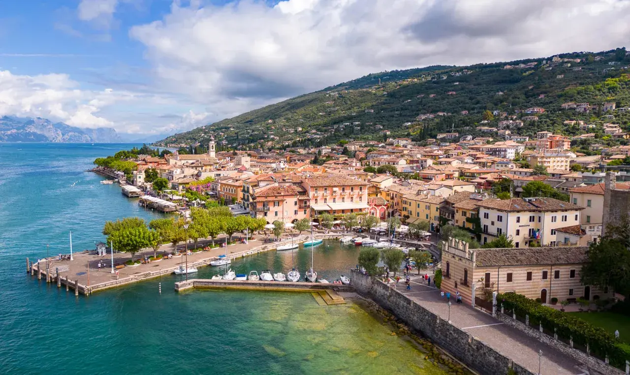 Vue aérienne de Torri del Benaco, un charmant village italien au bord du lac de Garde, avec ses maisons colorées, son port animé et ses collines verdoyantes.