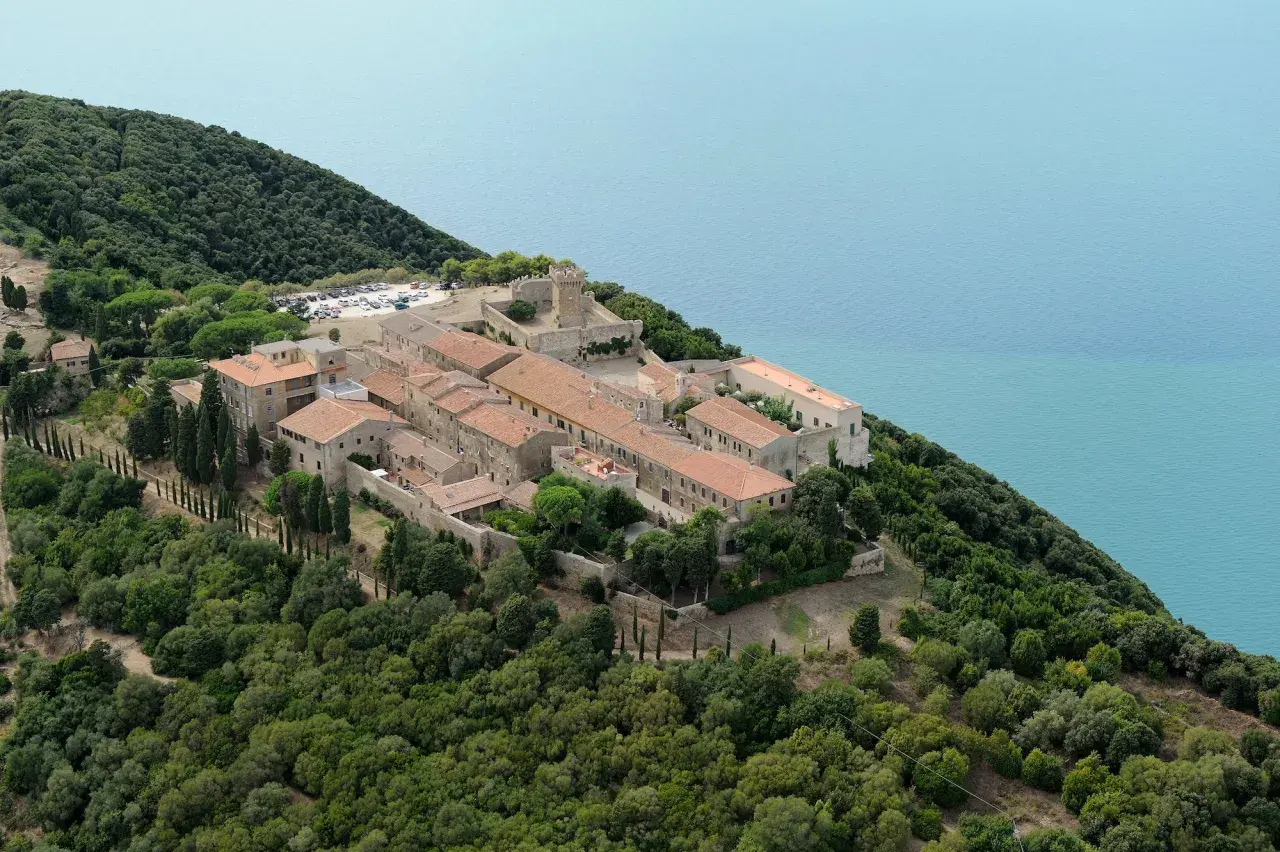 Vue aérienne de Populonia, Italie, un village médiéval perché sur une colline verdoyante surplombant la mer d'un bleu profond.