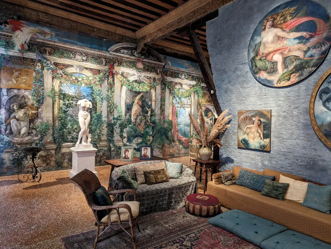Intérieur du museo Fortuny, avec une statue antique, des peintures murales luxuriantes et des meubles confortables.