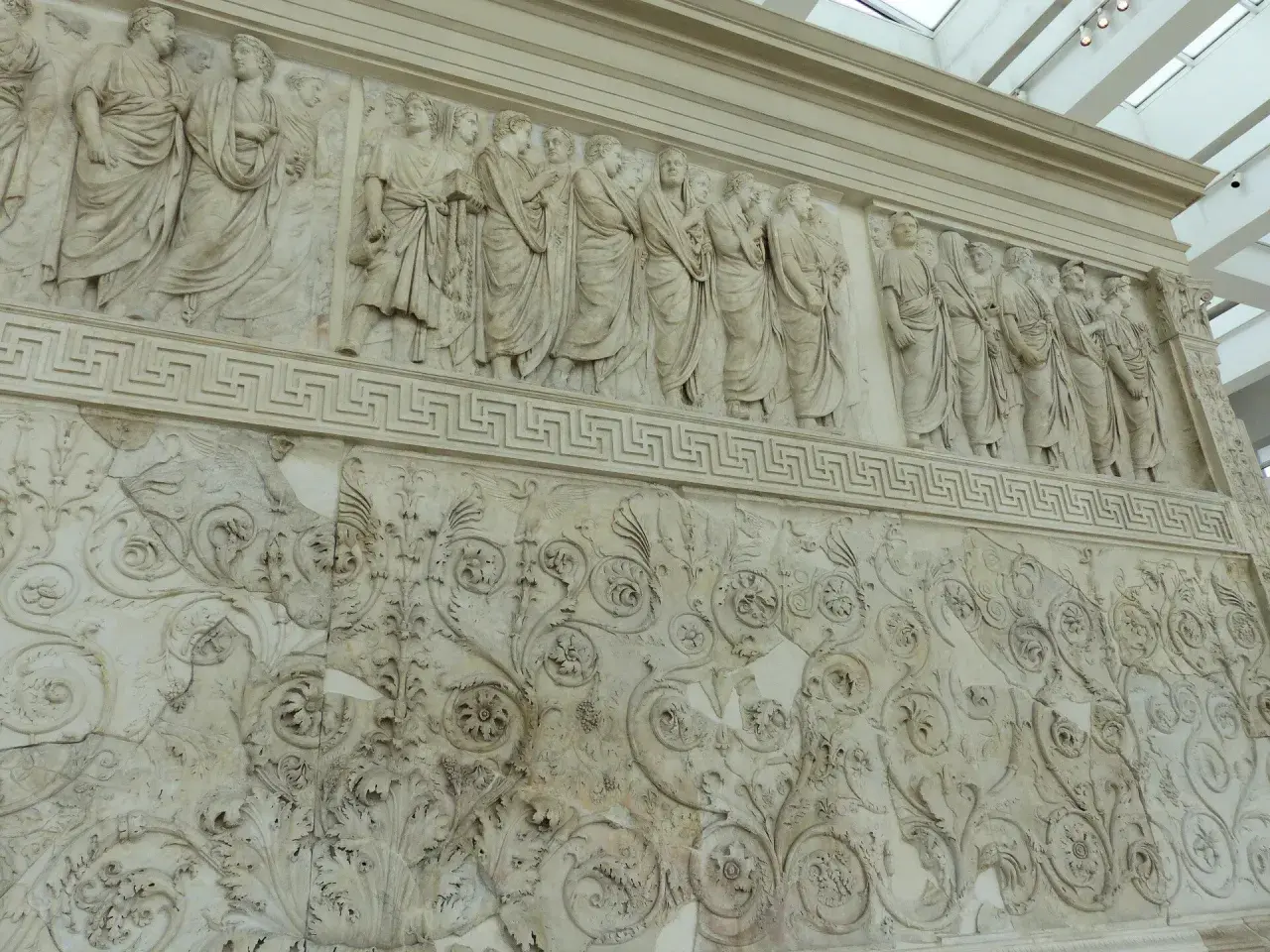 Bas-reliefs de l'Ara Pacis à Rome, représentant des figures toges et des motifs floraux complexes.