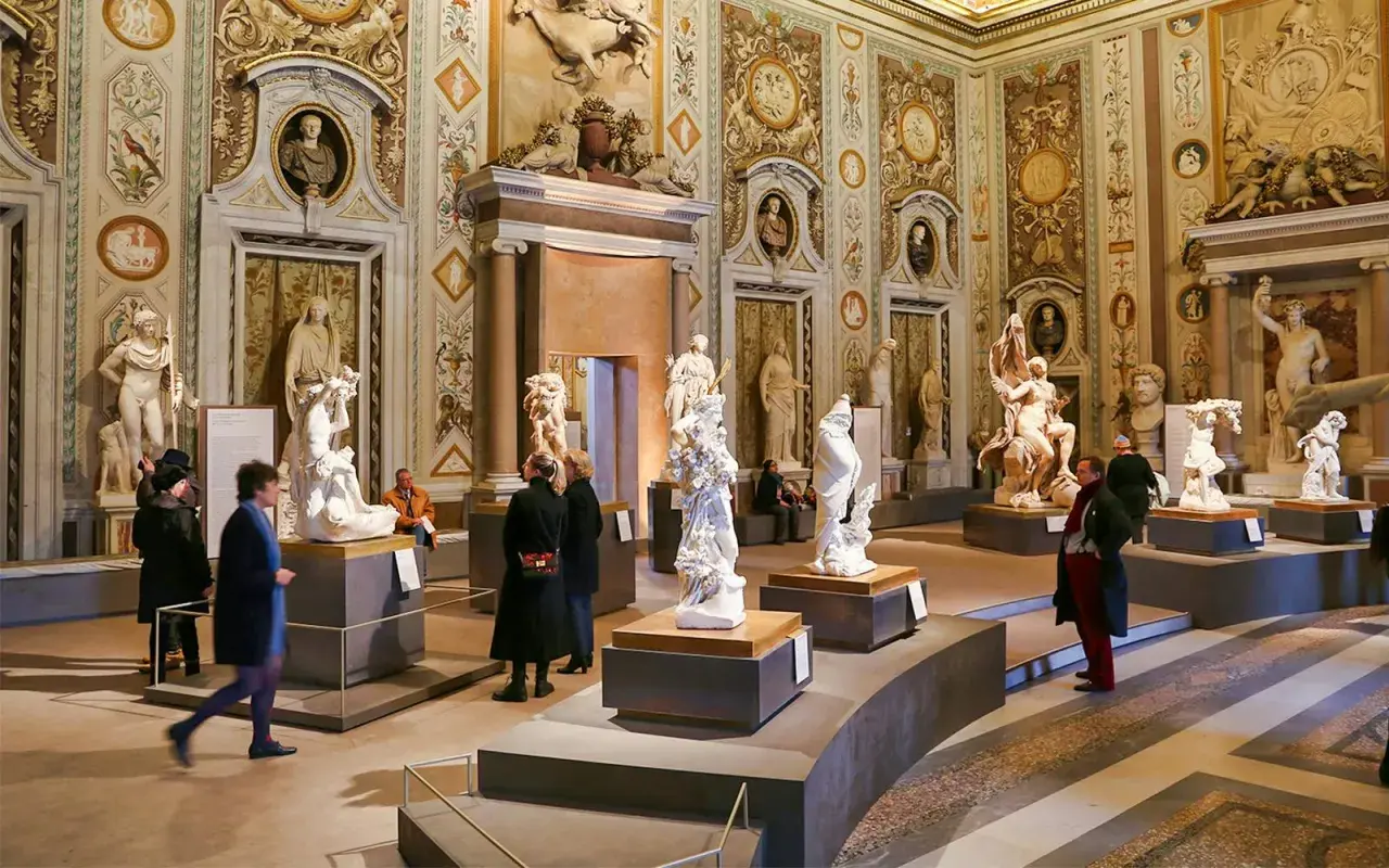Salle ornée de sculptures classiques à la Villa Borghese. Des visiteurs admirent des œuvres d'art dans un décor somptueux.