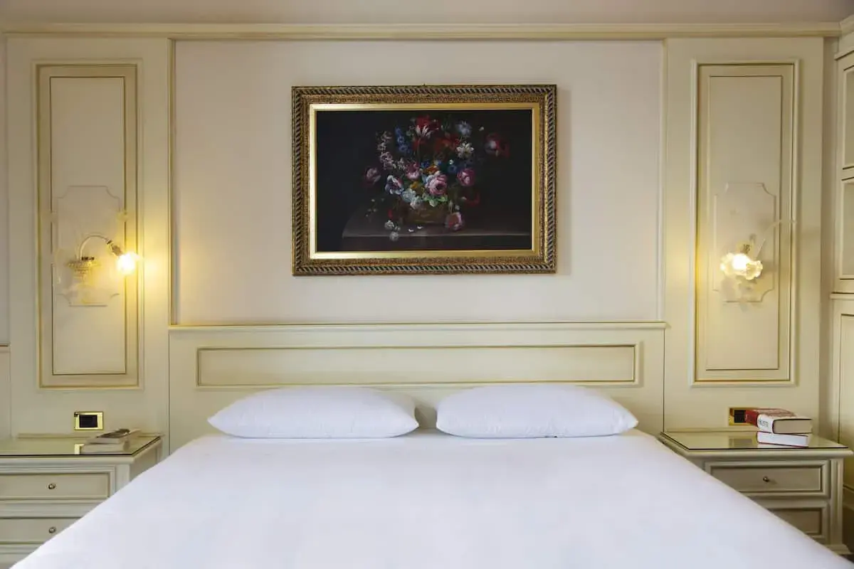 Chambre élégante d'un hôtel à Ghiffa sur le Lac Majeur, avec un tableau de fleurs au-dessus du lit.