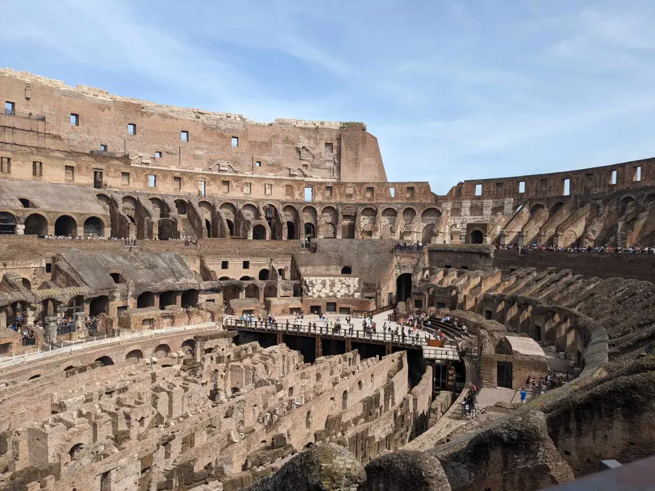 Vue intérieure du Colisée de Rome, vestiges de l'arène et des gradins, avec des touristes explorant ce monument historique.