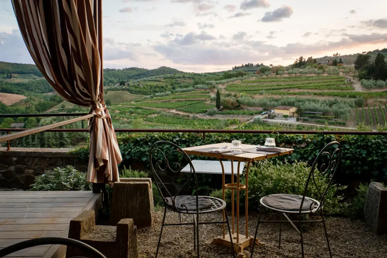 Terrasse d'agroturismo en Sicile avec vue sur les vignobles et les oliviers. Table dressée pour deux, prête pour un dîner paisible.