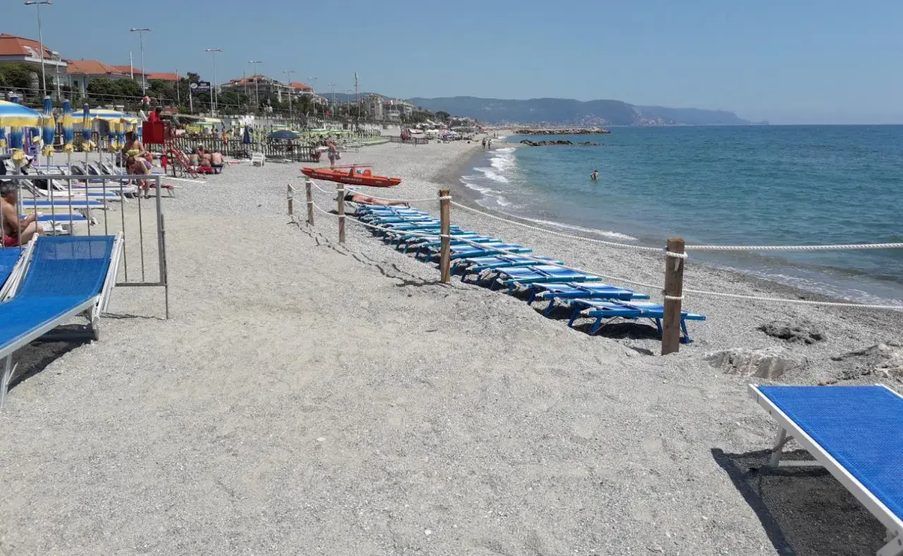 Plage de Loano, Italie, avec des chaises longues bleues alignées près de la mer Méditerranée.