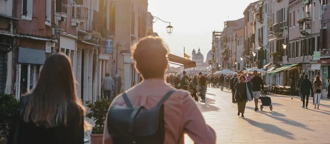 Promenade animée à Venise, près du Campo dei Mori, au coucher du soleil. Des passants flânent le long des bâtiments colorés.