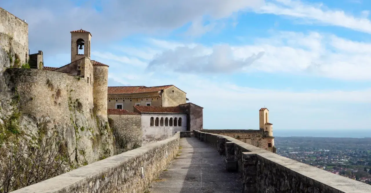 Chemin de pierre menant à un ancien château avec clocher, surplombant une ville en contrebas, typique de la massa italie.