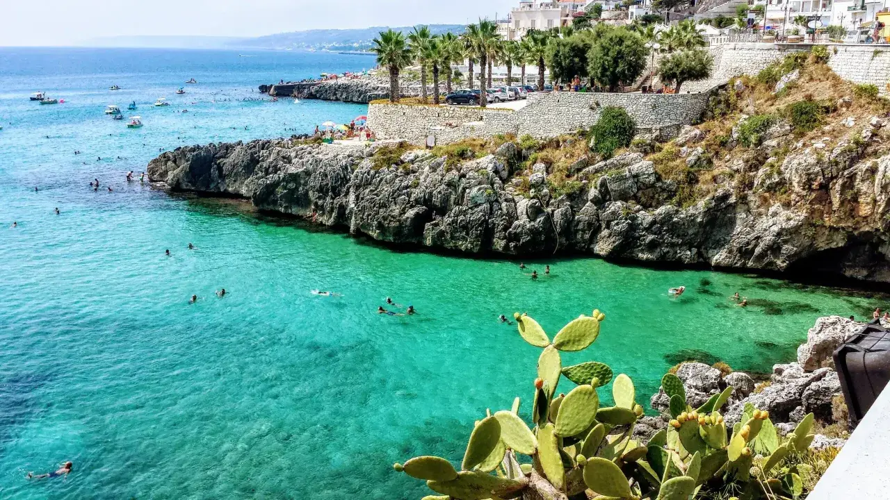 Plage rocheuse et eaux turquoise à Castro, Italie. Des baigneurs profitent du soleil et de la mer.