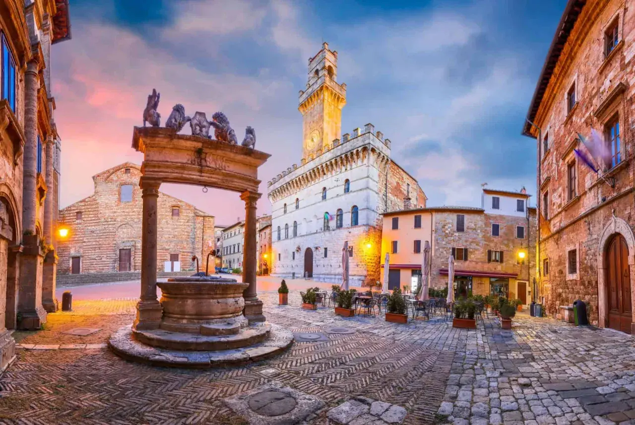 Place du peuple à Montepulciano, Toscane, avec sa fontaine ornée de lions et son hôtel de ville imposant.