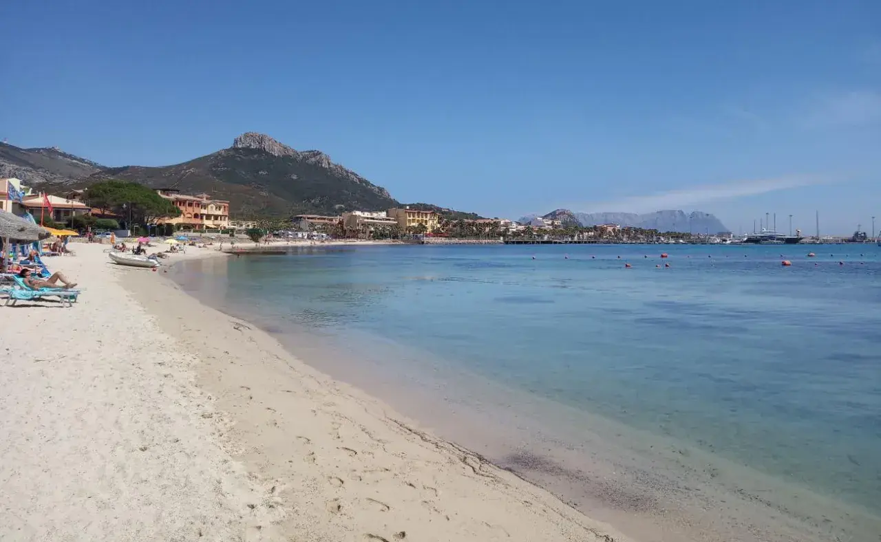 Plage de sable fin, eaux turquoise et montagnes en arrière-plan. Un rêve d'aranci in Sardegna.