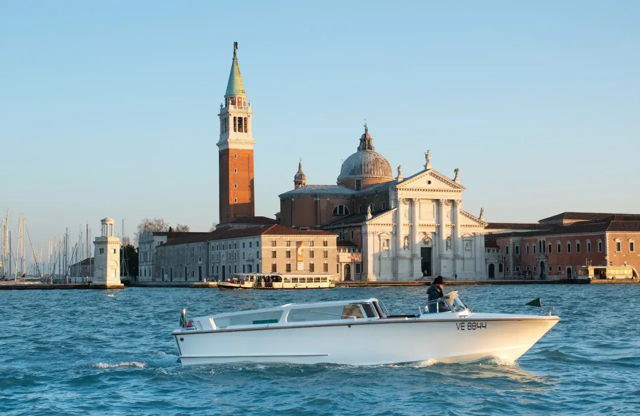 Taxi boat naviguant sur le Grand Canal, avec l'église San Giorgio Maggiore en arrière-plan. Idéal pour connaître le tarif taxi Venise.