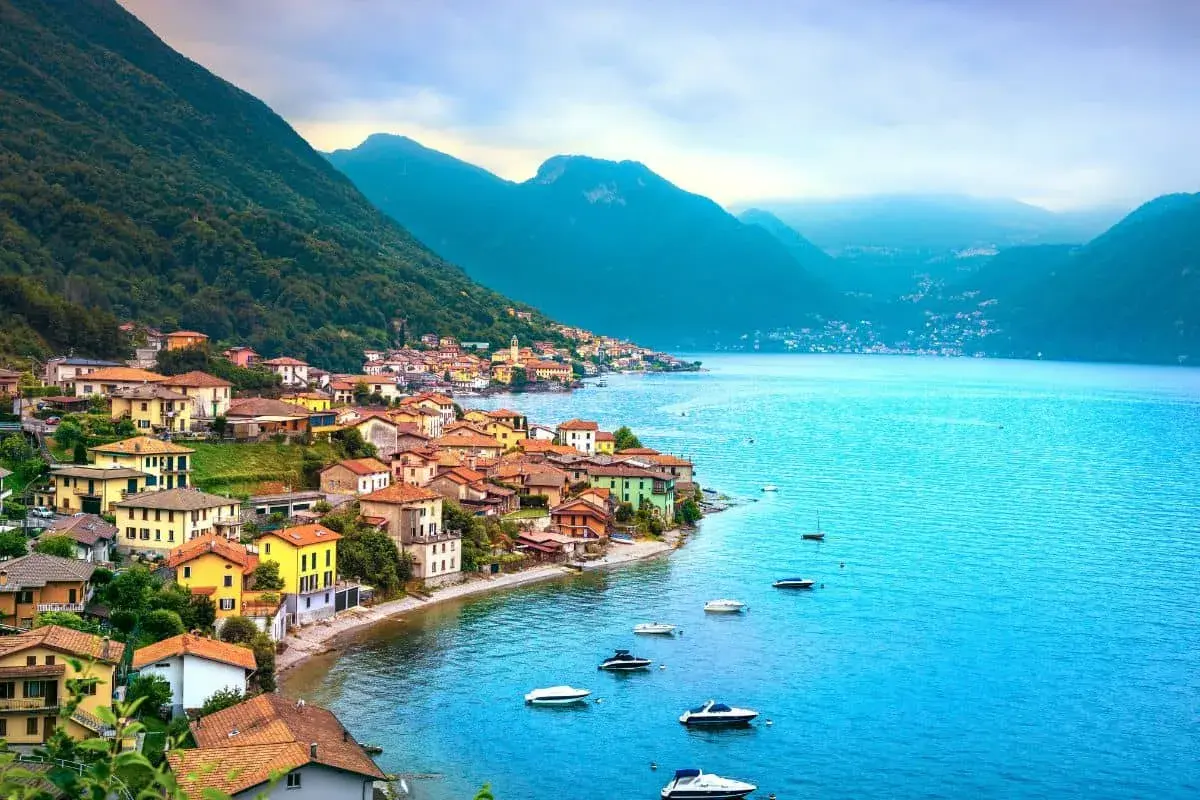 Village coloré au bord d'un lac bleu vif, niché au pied de montagnes verdoyantes. Un paysage typique des 3 lacs en Italie.
