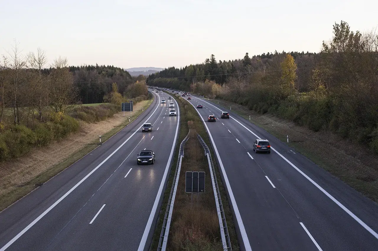 Voiture circulant en Italie sur une autoroute bordée d'arbres aux couleurs d'automne.