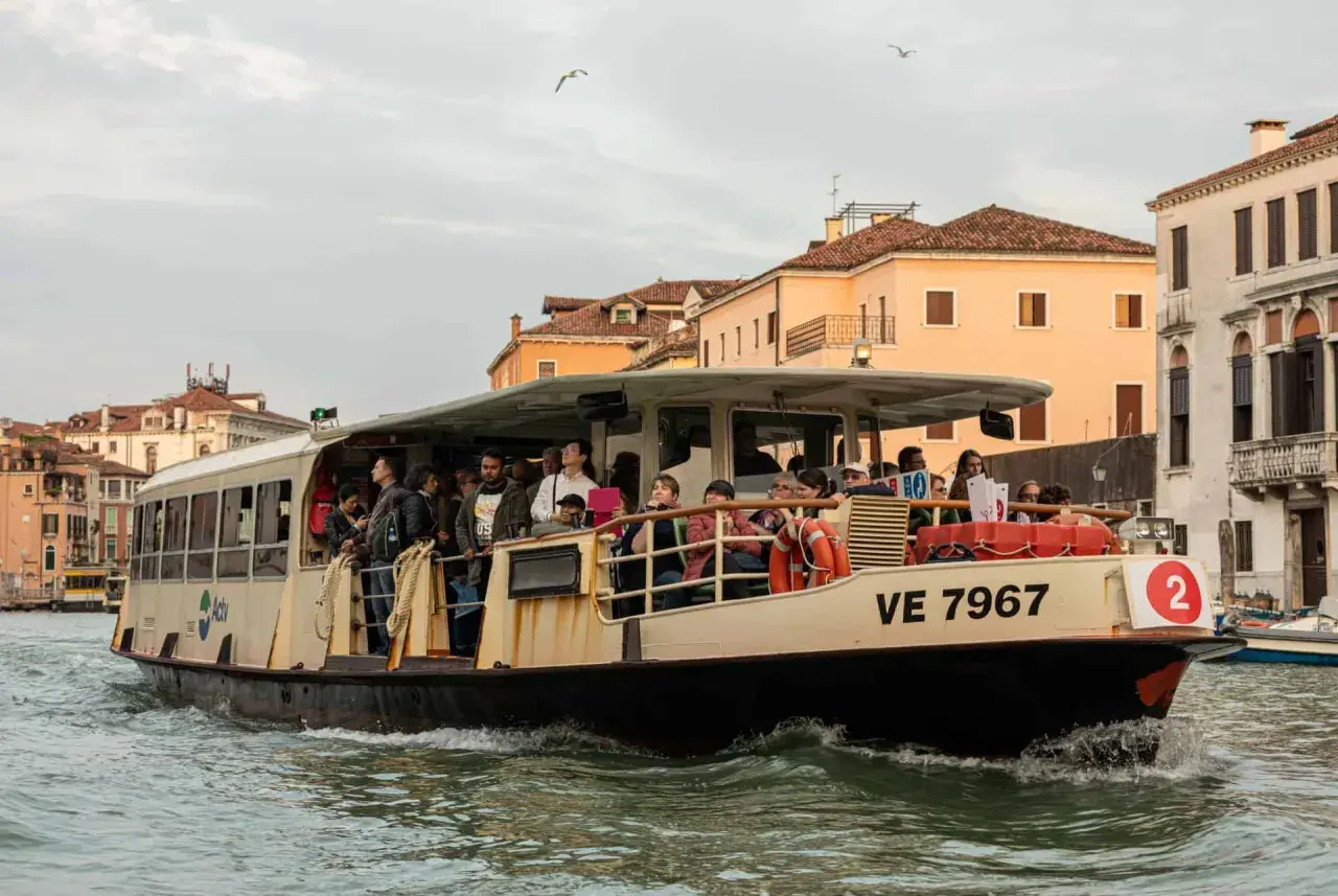 Un passager sur un vaporetto à Venise, naviguant sur les canaux bordés de bâtiments historiques.