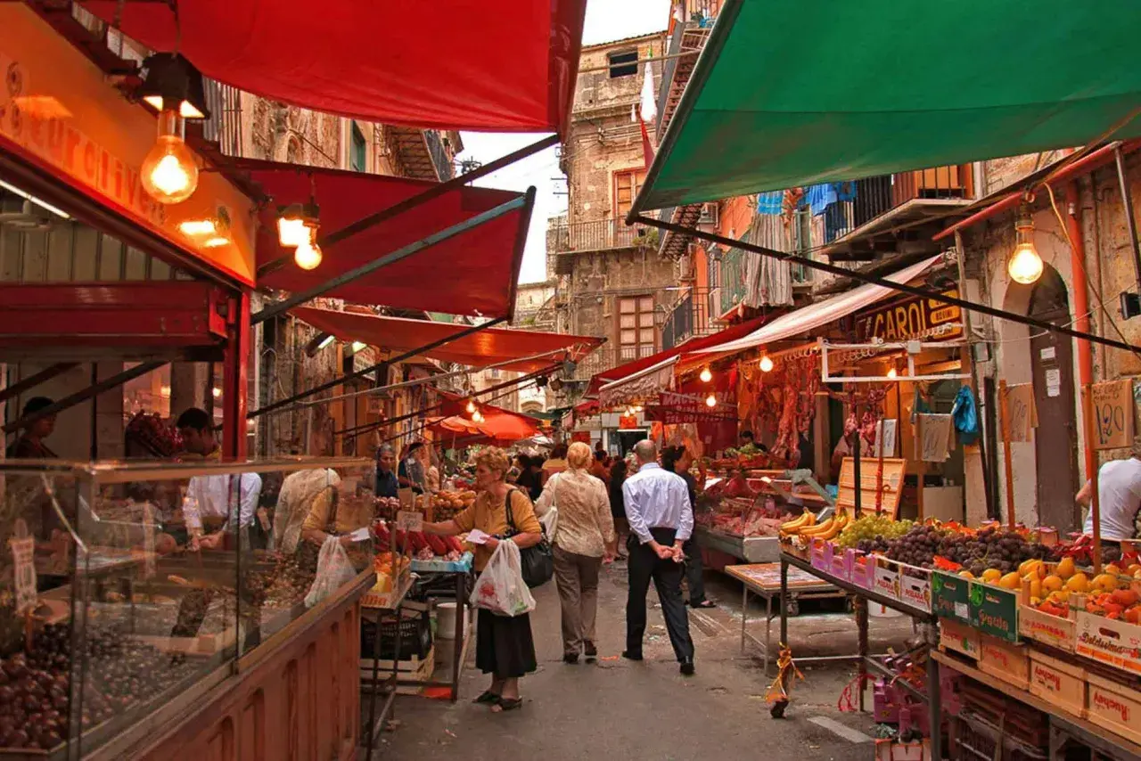 Ambiance animée au marché de la Vucciria à Palerme, avec des étals colorés, des fruits frais et des boucheries.