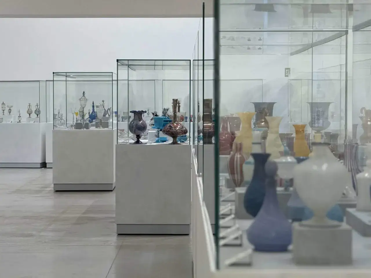 Exposition de vases en verre colorés et délicats dans des vitrines, un aperçu du musée du verre de Venise.
