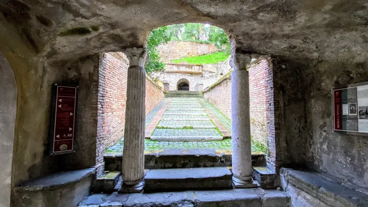 Escalier ancien sur l'Appia Antica à Rome, menant à une structure de pierre avec une arche.