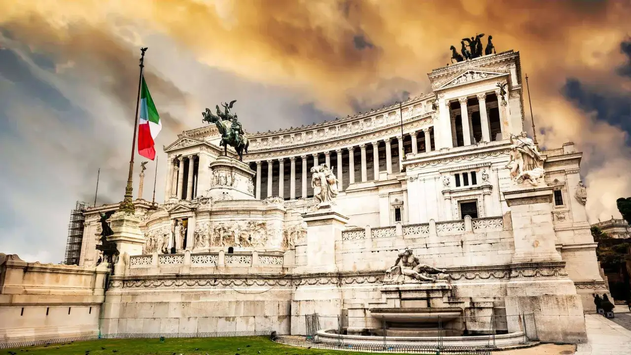 Le monument à Victor-Emmanuel II à Rome, avec son drapeau italien flottant sous un ciel orageux.