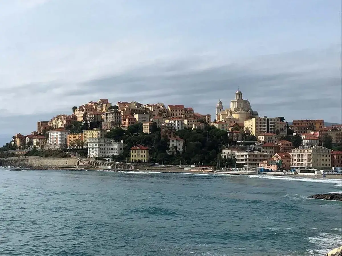 Vue panoramique d'une ville côtière colorée perchée sur une colline, avec une église imposante, en Italie, Imperia.