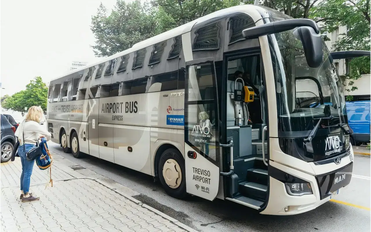 Un bus navette pour l'aéroport de Trévise, un bus venise, attend une passagère sur le trottoir.