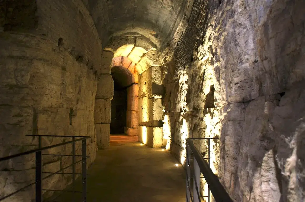 Couloir voûté en pierre du Colisée, éclairé par des lumières chaudes. La durée de la visite du Colisée peut varier, mais ce passage donne une idée de son immensité.