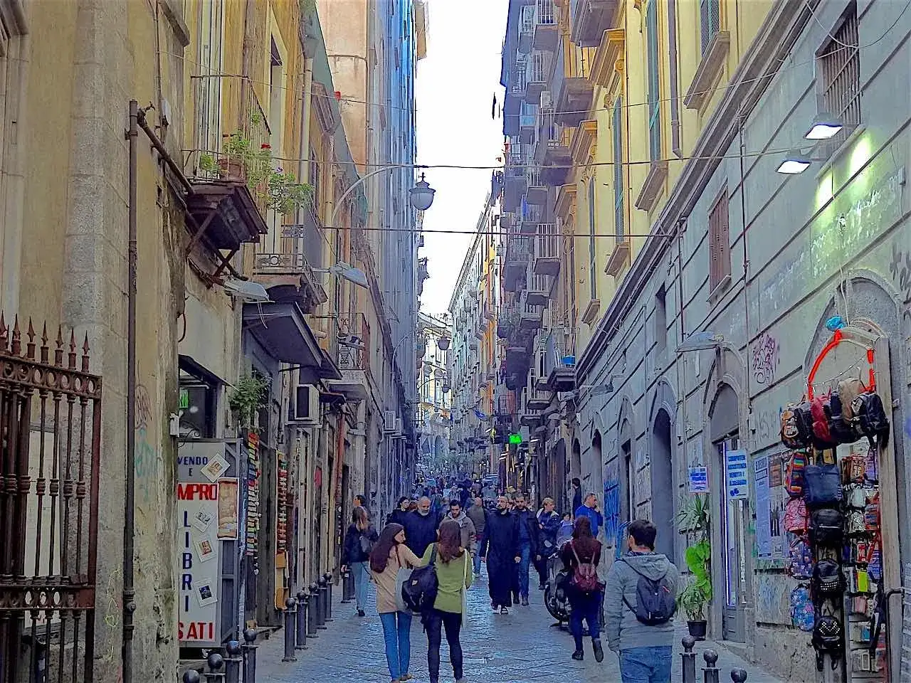 Visiter Naples en 1 jour : une rue animée bordée de bâtiments colorés, de boutiques et de passants.