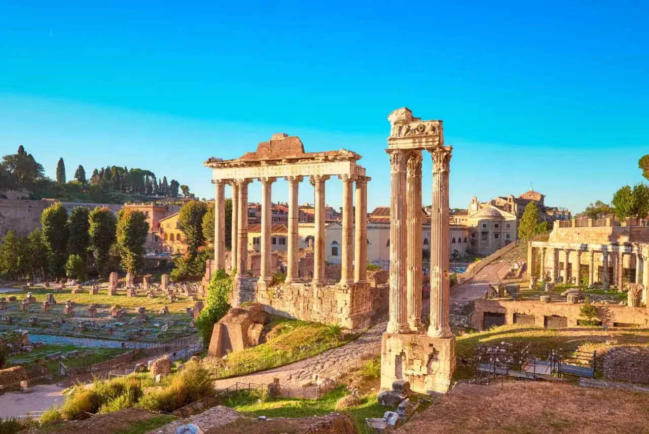 Ruines antiques sur le mont Palatin à Rome, avec des colonnes imposantes et des vestiges de bâtiments sous un ciel bleu clair.