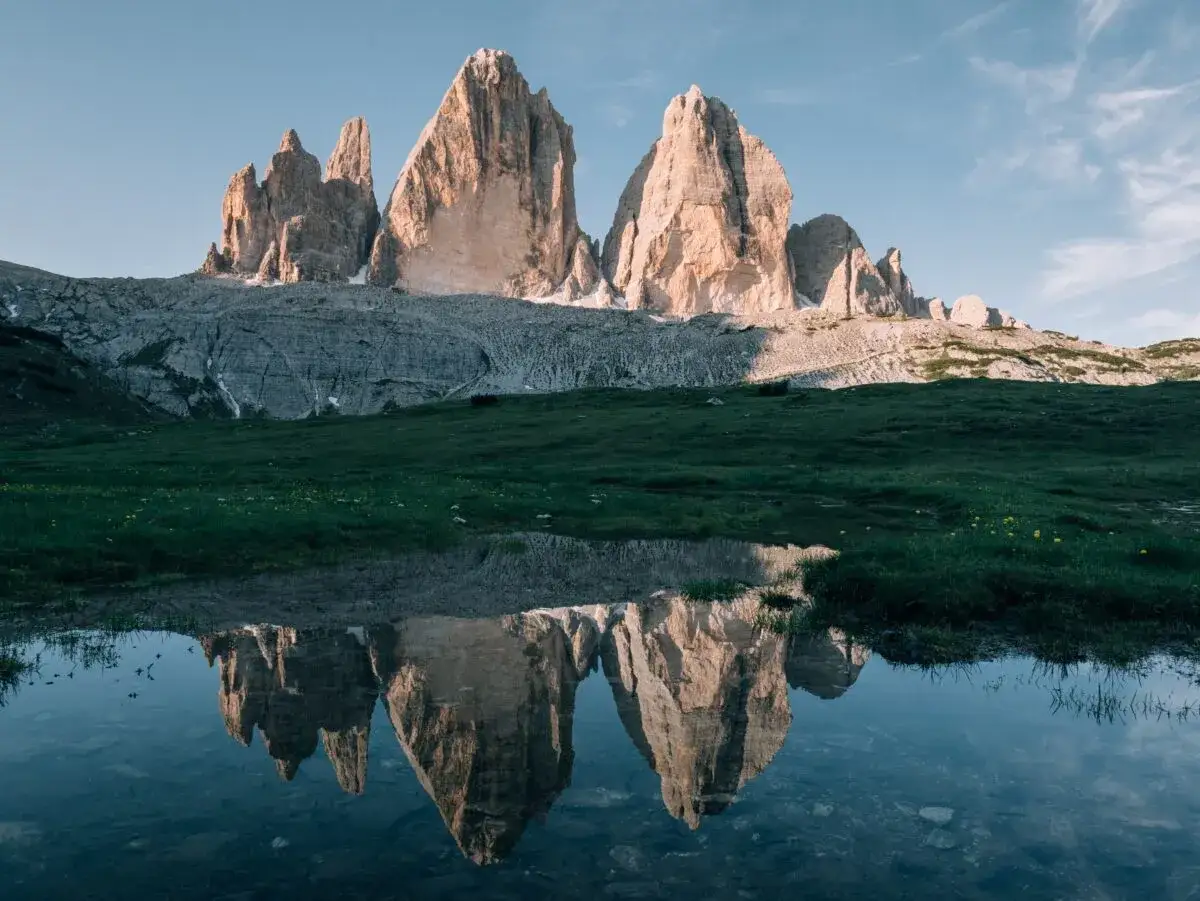 Les Trois Cimes de Lavaredo se reflètent dans un étang près de Misurina, sous un ciel bleu clair.