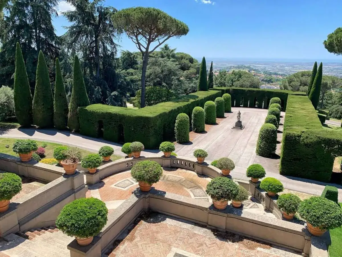Jardins à la Villa Barberini, avec des haies taillées, des cyprès élancés et une vue panoramique sur la campagne.