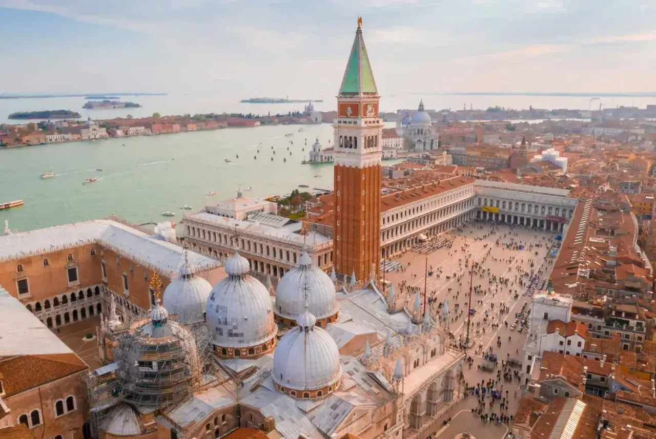 Vue aérienne de Venise, le campanile se dresse fièrement au-dessus de la place Saint-Marc animée, avec le canal scintillant en arrière-plan.