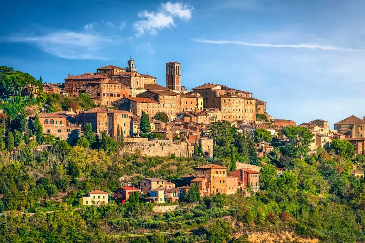 Vue panoramique de Montepulciano, un village toscan perché sur une colline, avec ses maisons en briques et ses tours médiévales baignées de soleil.