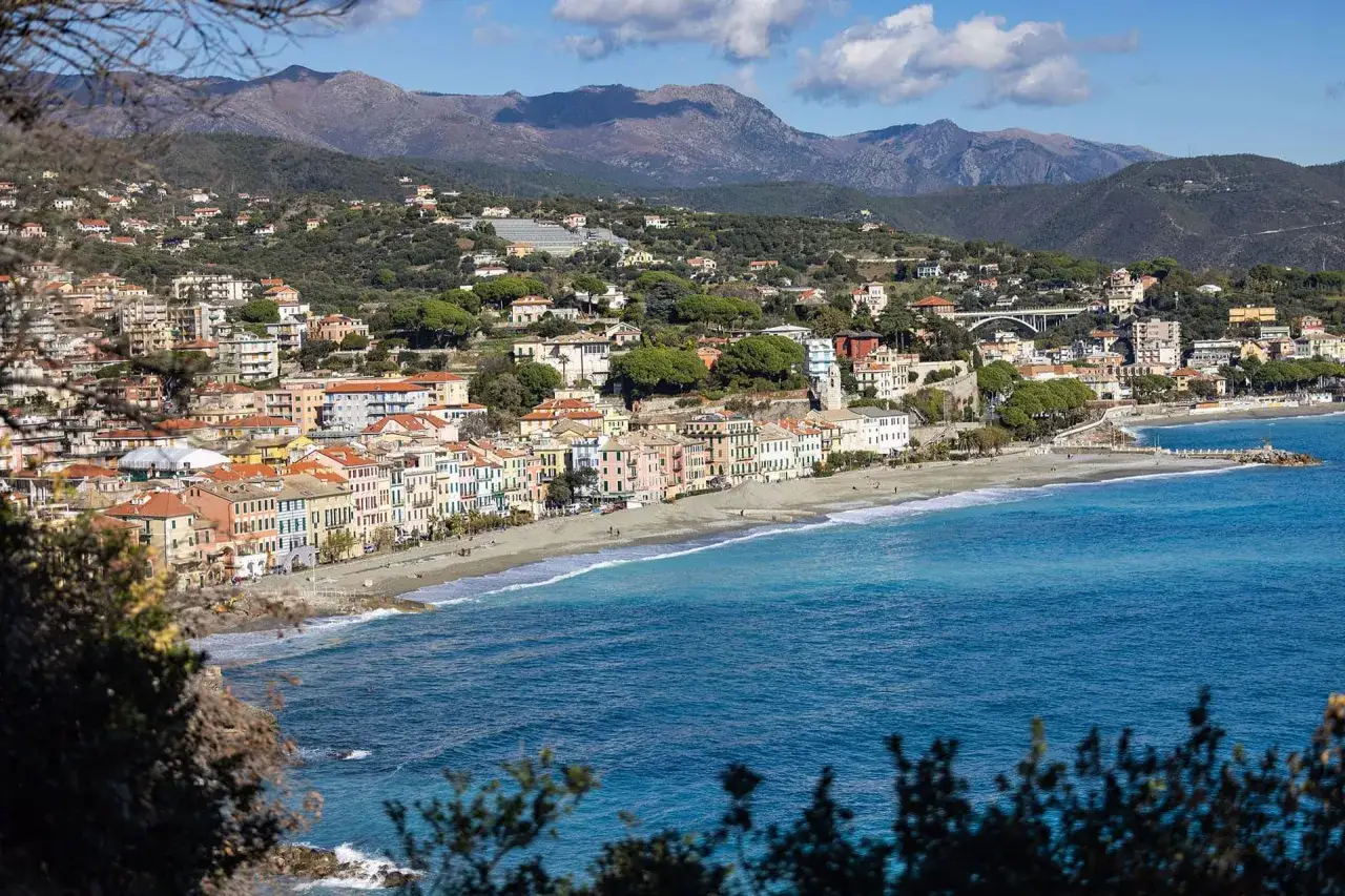 Vue panoramique de Celle Ligure, une ville côtière italienne aux maisons colorées, bordée par une plage de galets et la mer d'un bleu profond.