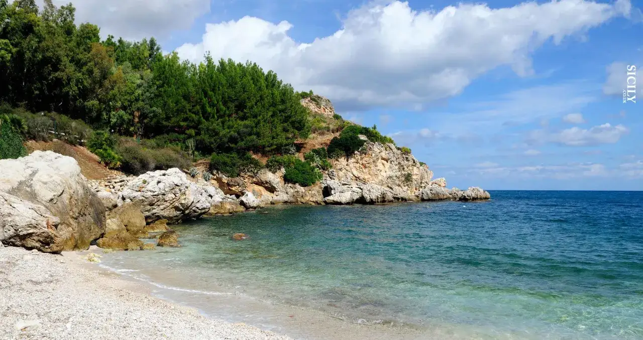 Plage de galets et mer turquoise près de Mazara del Vallo, Italie. Falaises rocheuses couvertes de végétation luxuriante.
