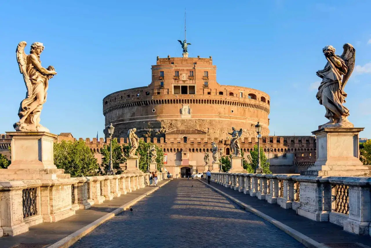 Le Pont Saint-Ange mène au Château Saint-Ange, un site incontournable de Rome, orné de statues d'anges sous un ciel bleu.