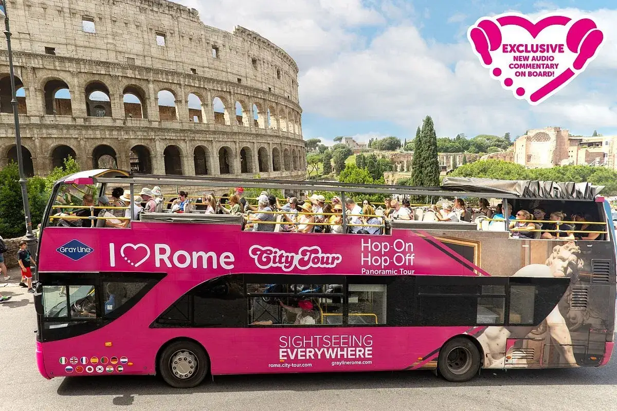 Bus touristique rose devant le Colisée. Profitez d'un tour de Rome en bus avec commentaires audio exclusifs.