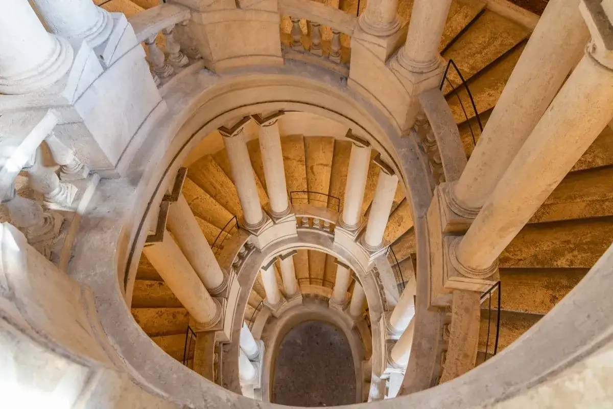 Escalier en colimaçon spectaculaire au Palazzo Barberini, avec ses colonnes imposantes et ses marches dorées.