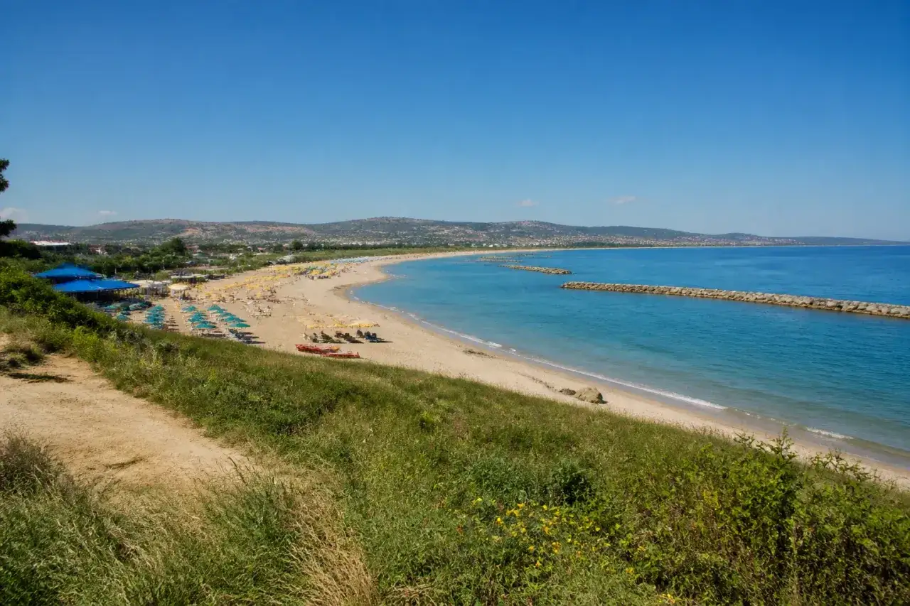 Plage de Pescara, Italie, avec des parasols colorés, des transats et des digues en pierre dans la mer Adriatique sous un ciel bleu.